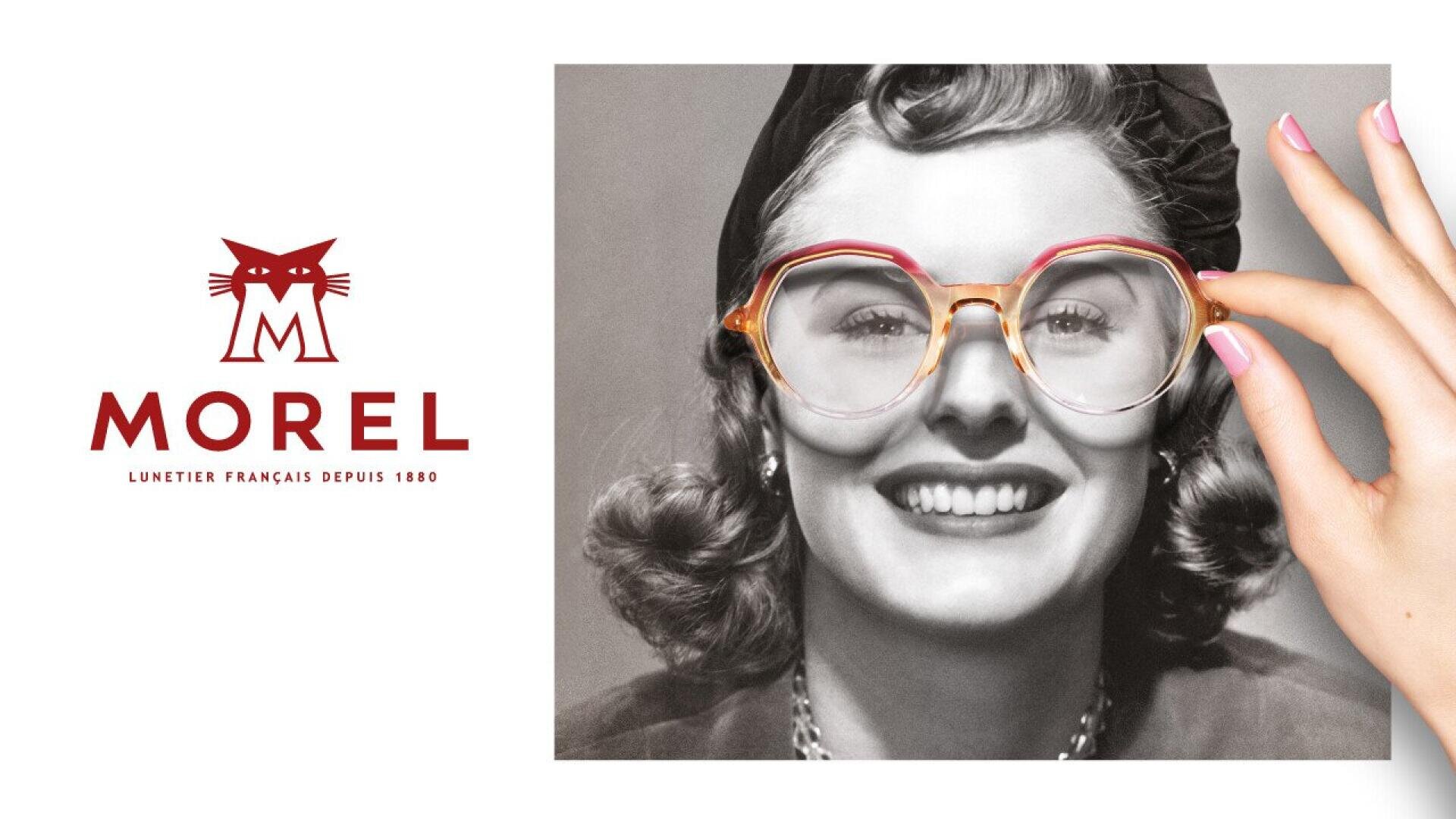 A black-and-white portrait of a smiling woman in vintage attire, with a modern hand holding oversized glasses in color over her face. To the left is the red Morel logo with a stylized cat and French text.