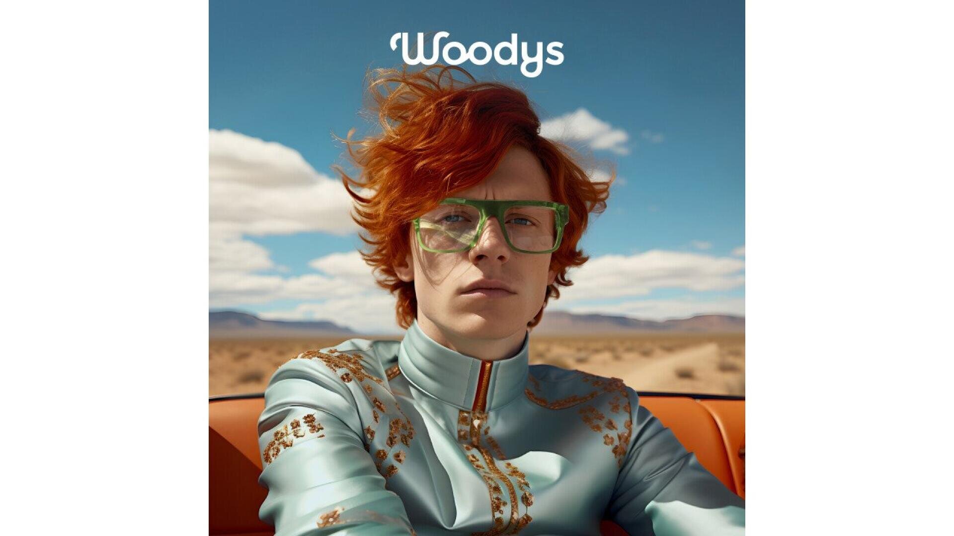 A person with bright red hair and large green glasses sits in a car, wearing a light blue jacket with gold details. The background shows a desert landscape and the word Woodys appears above their head.