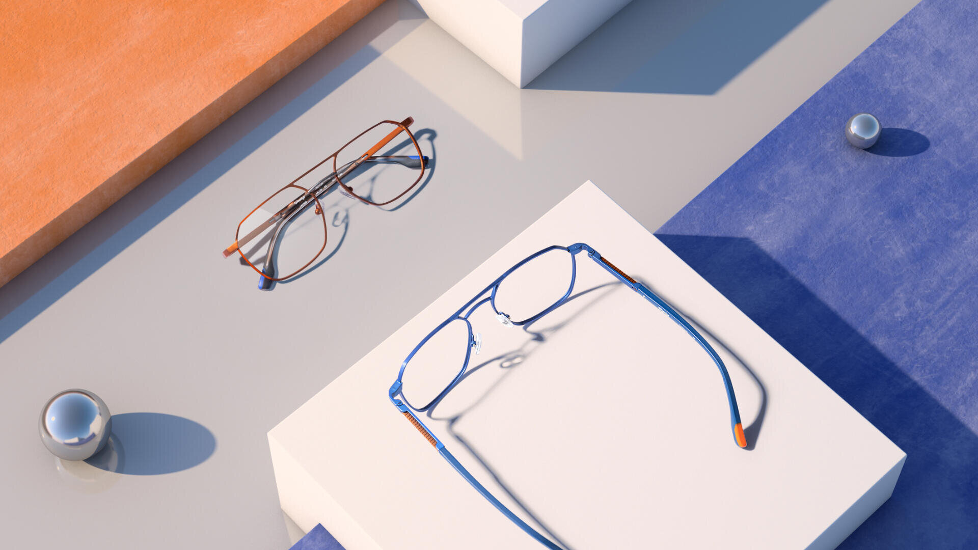 Zwei Brillen liegen auf geometrischen Plattformen – eine braune auf hellgrauer Oberfläche und eine blaue auf weißer. Der Hintergrund ist mit orangefarbenen und blauen Oberflächen und reflektierenden silbernen Kugeln verziert.
