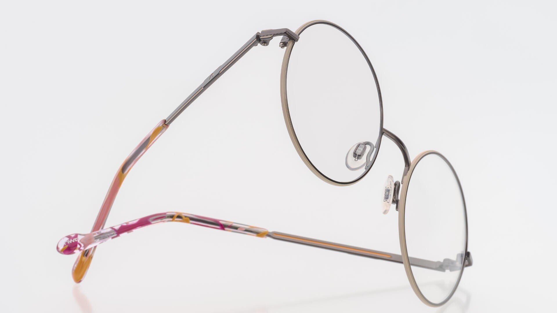 Runde Brille mit dünnem Rahmen, Metallrändern und klaren Gläsern sowie Bügelenden mit Schildpattmuster vor weißem Hintergrund.