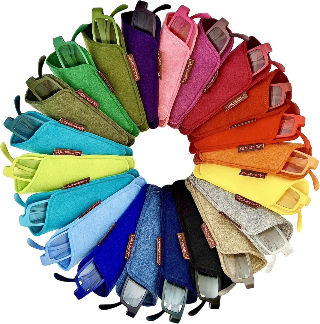 A circular arrangement of colorful eyeglass cases in a gradient rainbow pattern, with each case containing one pair of glasses. Colors include shades of green, blue, purple, pink, red, orange, yellow and beige.