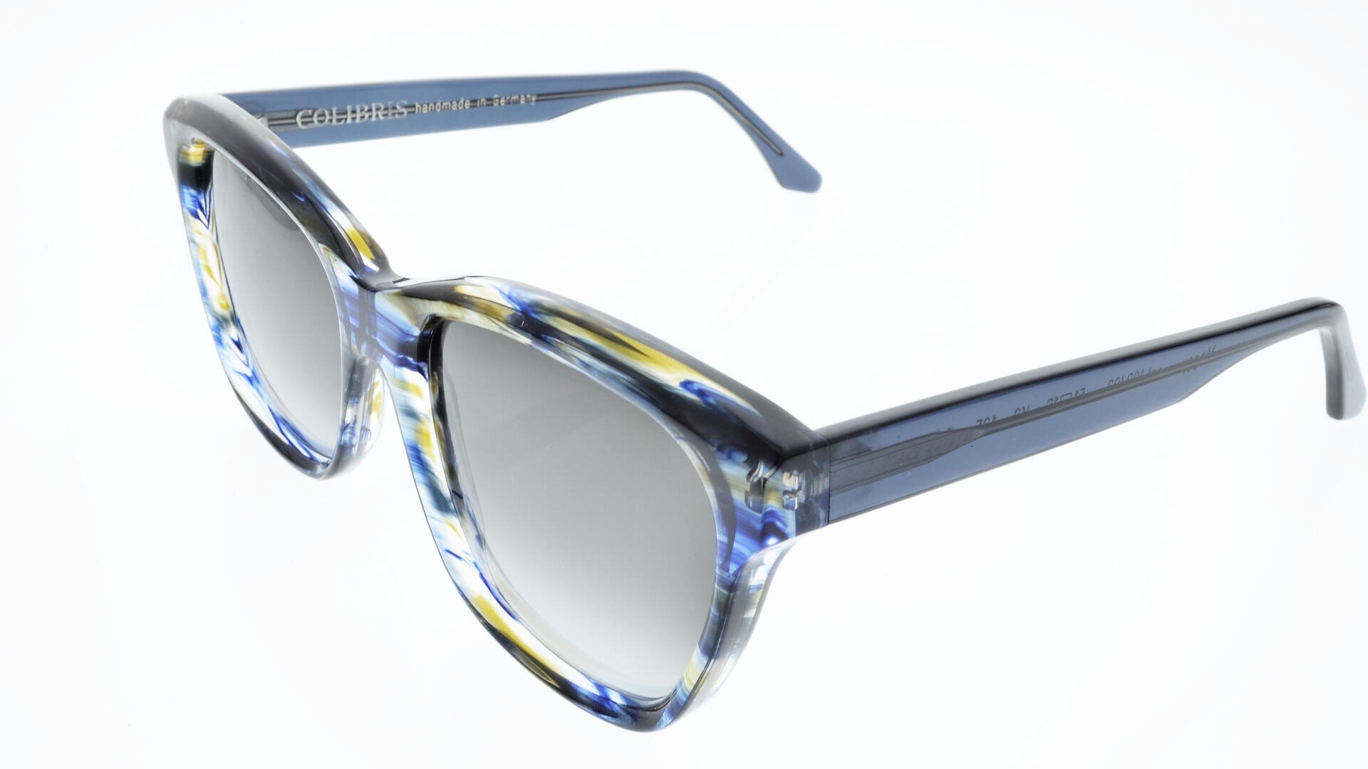 Eine stylische Sonnenbrille mit dickem, blau und gelb marmoriertem Rahmen und grau getönten Gläsern vor weißem Hintergrund.