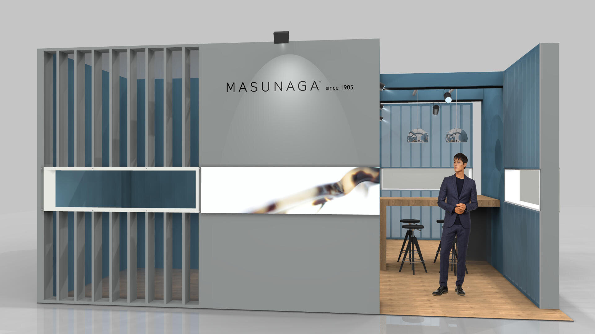 Ein moderner Messestand von MASUNAGA since 1905 zeigt einen Mann im Anzug am Eingang. Der Stand ist minimalistisch gestaltet und verfügt über blaue und graue Paneele, Ausstellungsflächen und einen Holzboden.