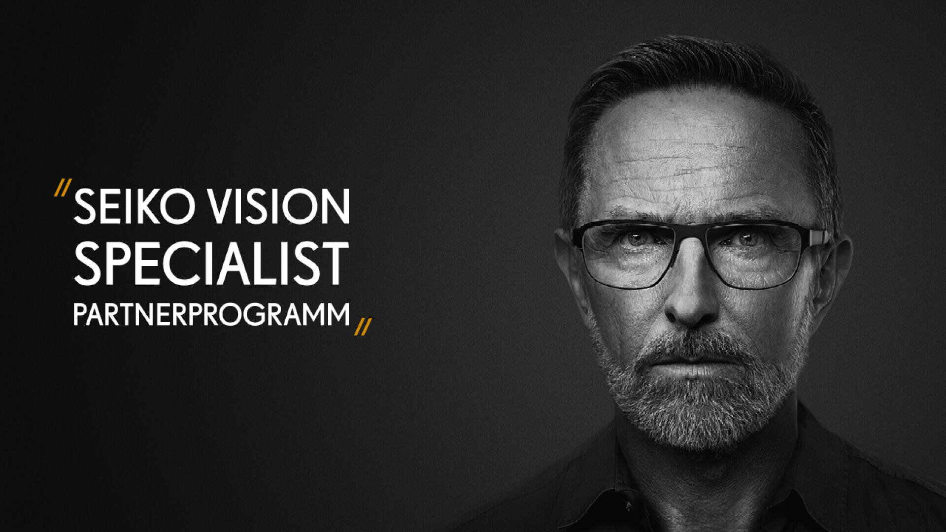 Ein Mann mit kurzen Haaren, Bart und Brille blickt vor dunklem Hintergrund ernst in die Kamera. Links steht in fetten weißen und gelben Buchstaben: SEIKO VISION SPECIALIST PARTNERPROGRAMM.