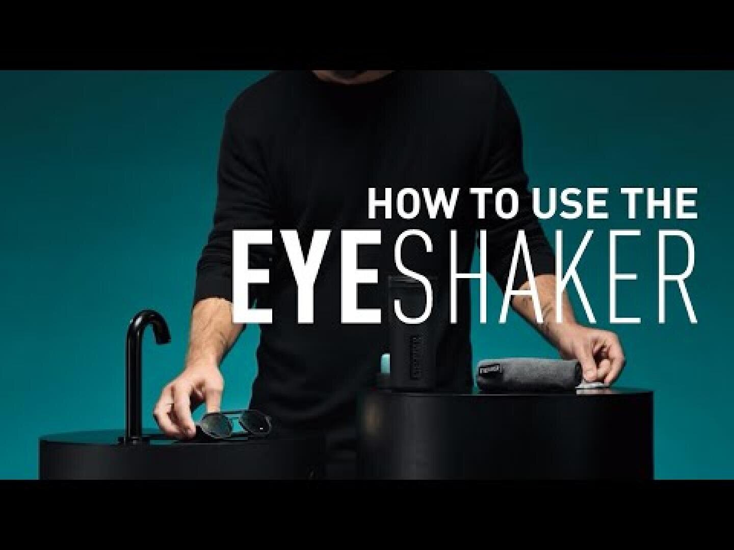 Eine schwarz gekleidete Person steht hinter einem Tresen mit einer Brille, einem Reinigungsgerät und einem Tuch. In einem großen Text ist zu lesen: Wie man den EyeShaker benutzt. Der Hintergrund ist türkisfarben.