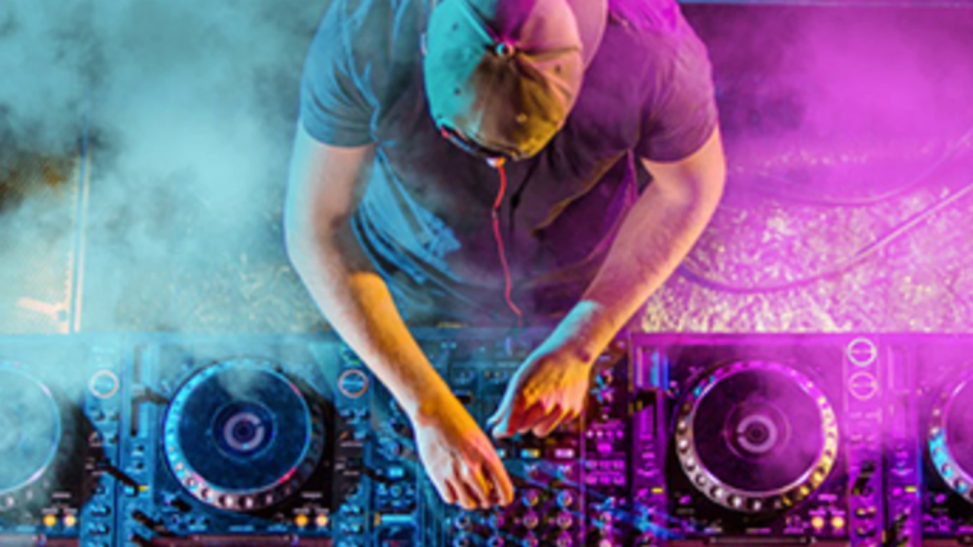 A DJ wearing a hat and headphones mixes music on a colorful DJ console surrounded by smoke and vibrant purple and blue lights, viewed from above.