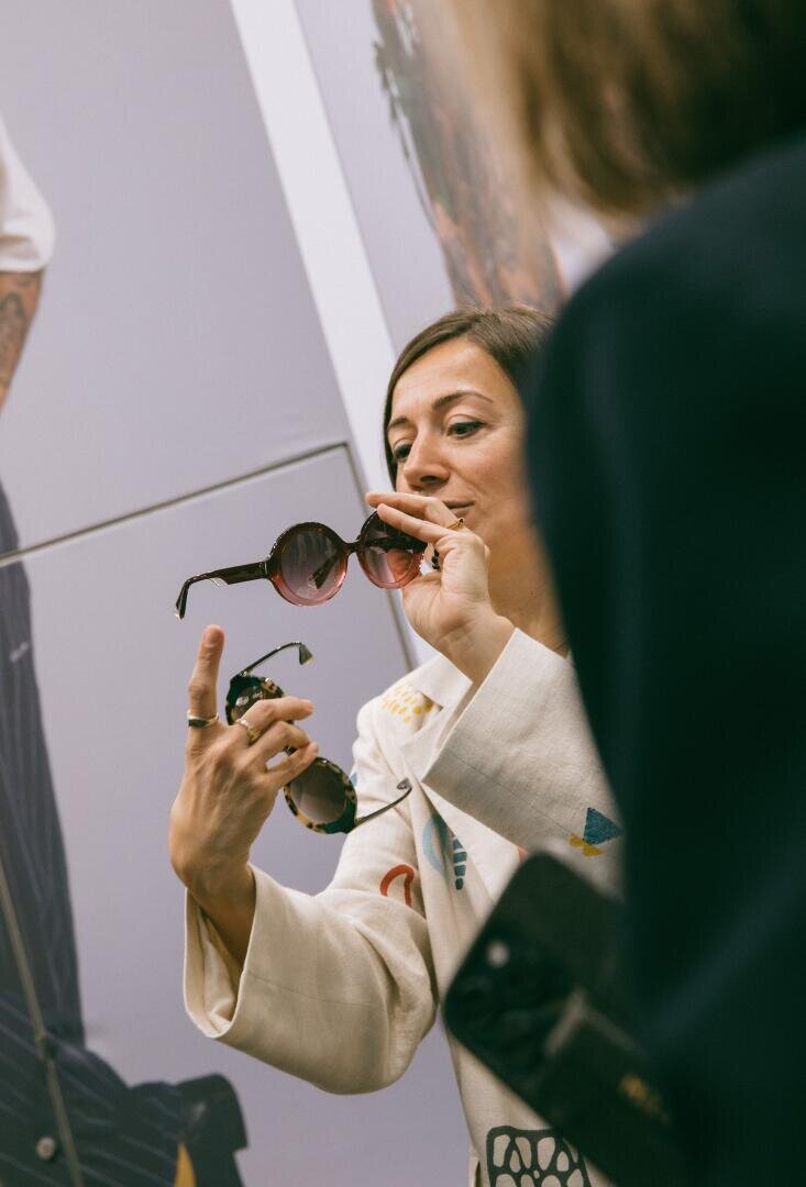 A woman with sunglasses in front of a mirror.