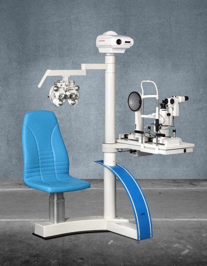 Eine moderne augenärztliche Untersuchungsstation mit einem blauen Patientenstuhl, Diagnoseinstrumenten und einer montierten Lampe vor einer grauen Betonwand.