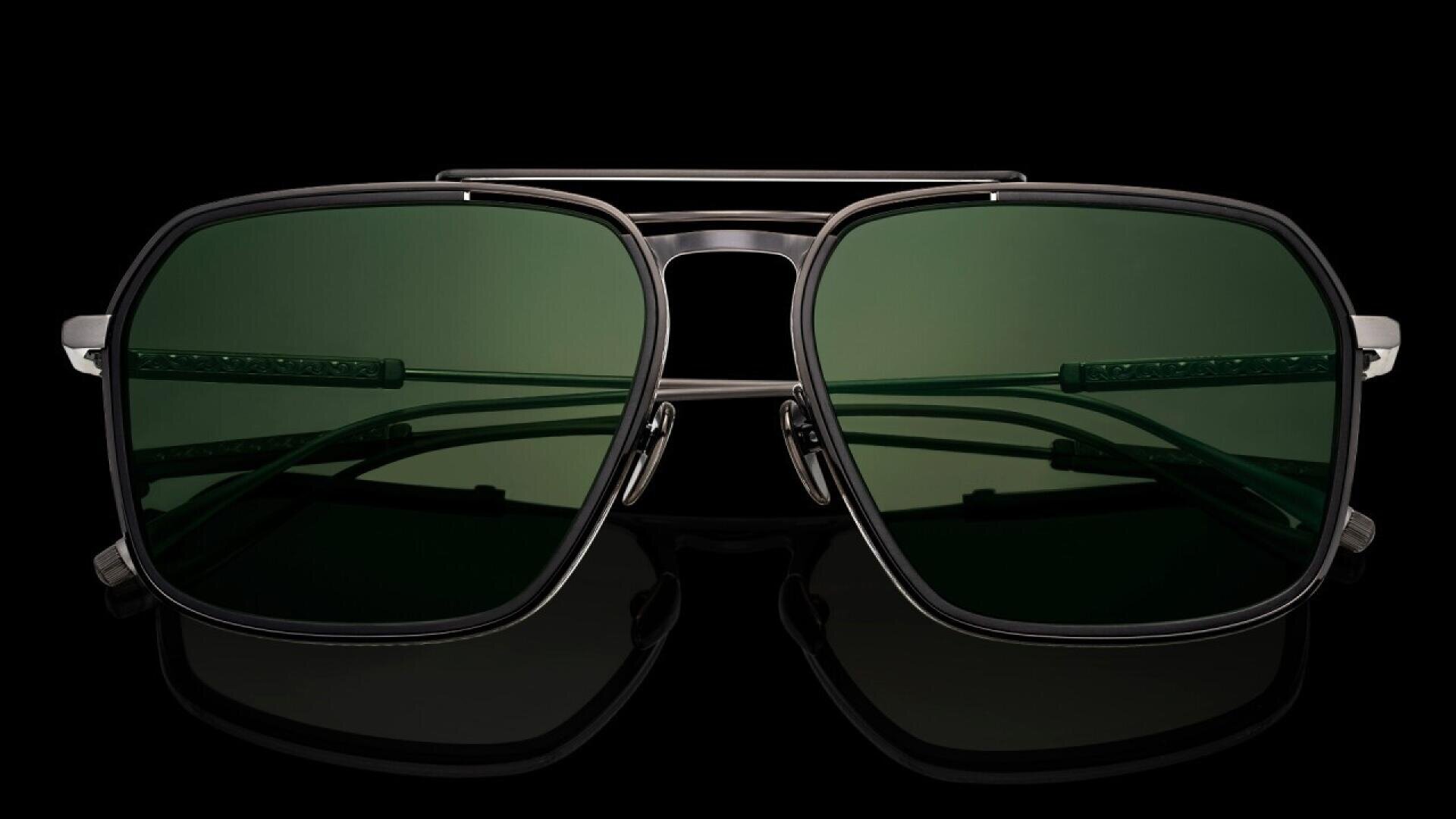 Close-up of a pair of dark green, square-lens sunglasses with a thin black metal frame and double bridge, set against a black background.